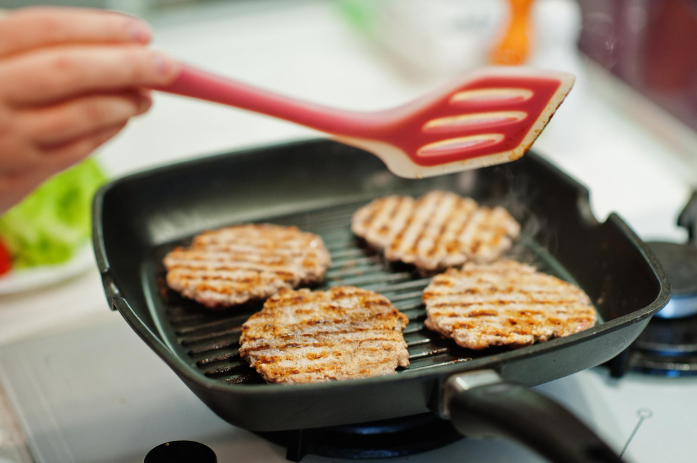 seseorang sedang memassak daging di griddle